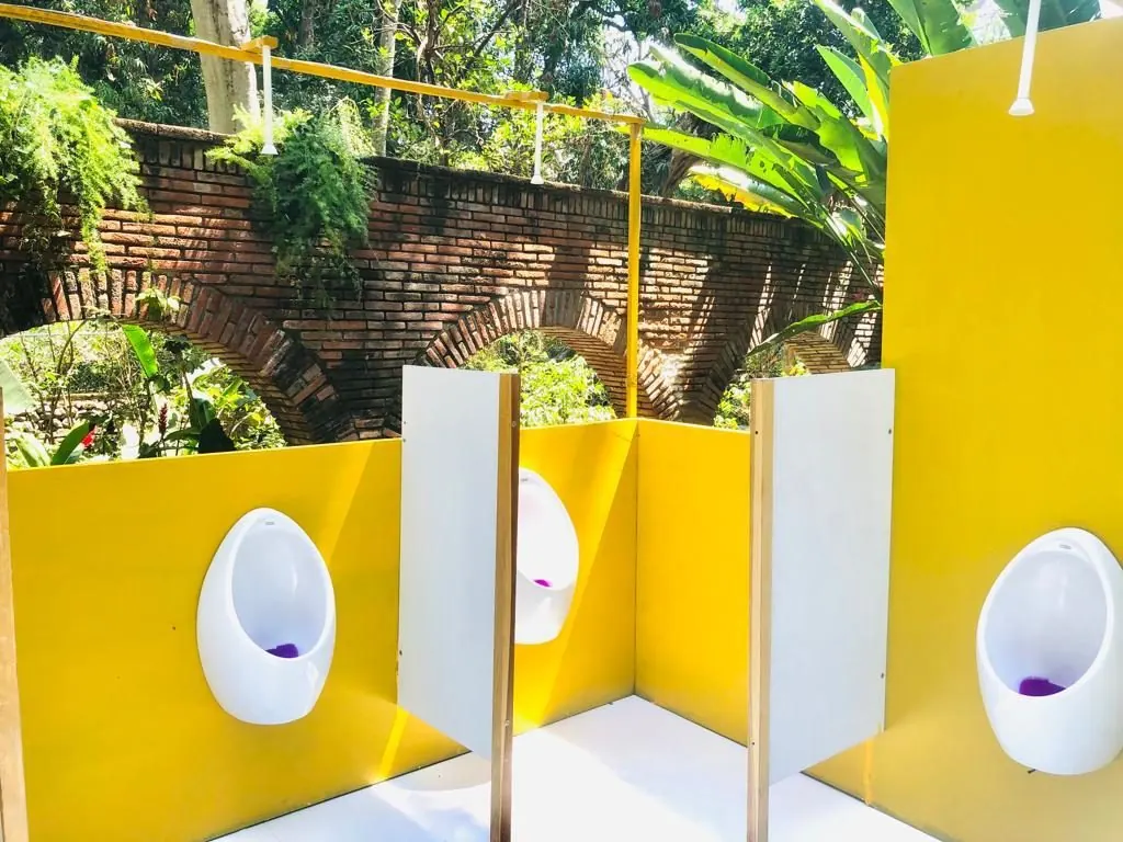 Mingitorios con divisores en un baño de lujo al aire libre, con arcos de ladrillo al fondo