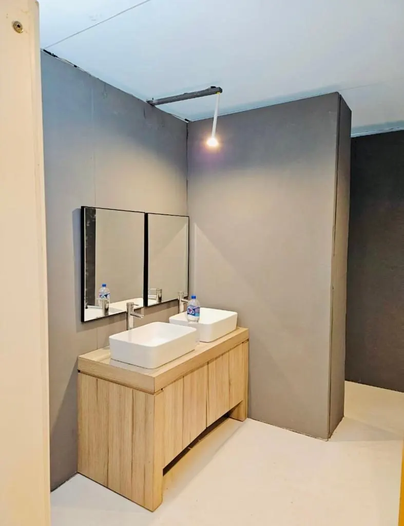 Mueble de madera con dos lavabos blancos y espejos en un baño portátil de lujo VIP
