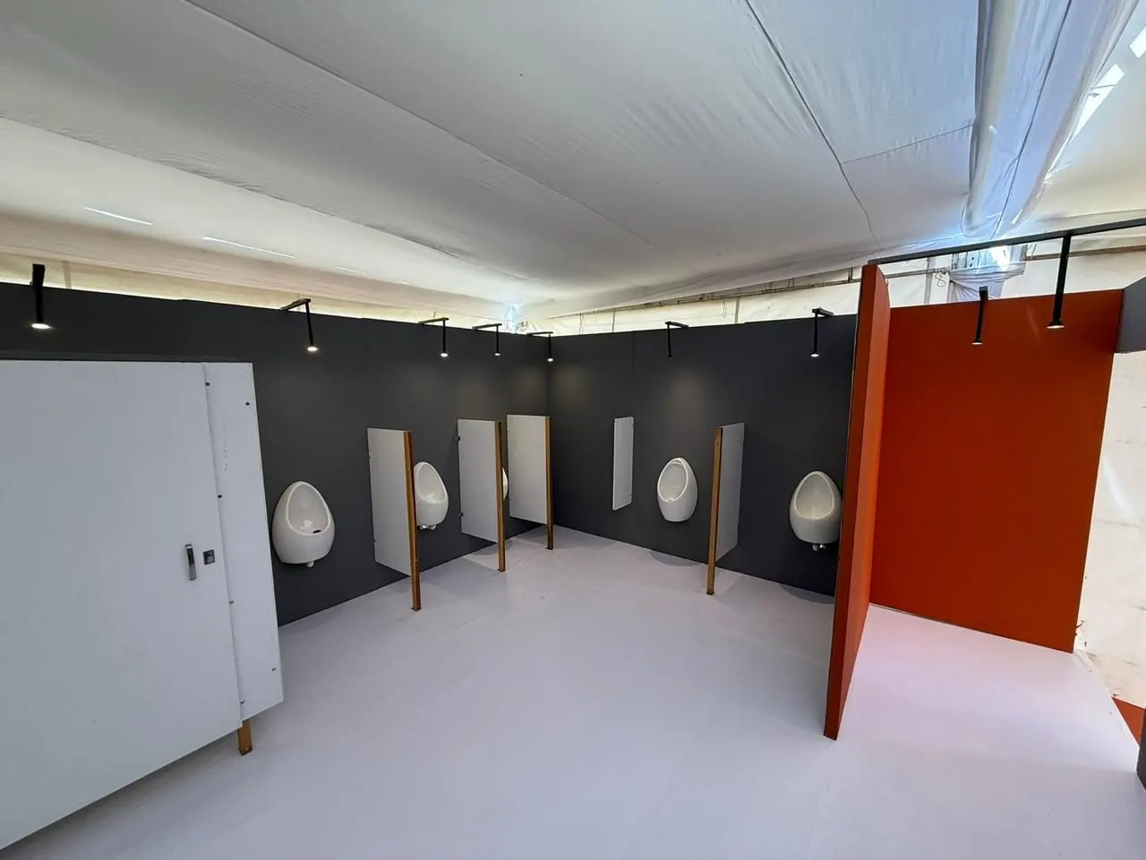 Lado de caballeros de un baño de lujo VIP, con mingitorios de porcelana y divisores