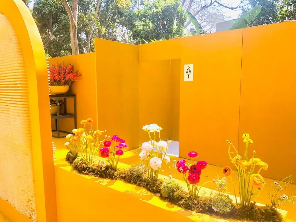 Jardinera con flores frente a los muros amarillos de un baño de lujo al aire libre
