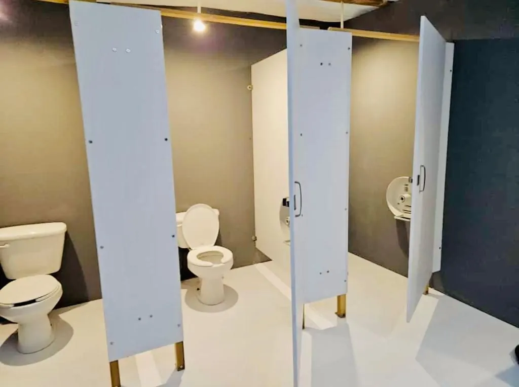 Cubículos con inodoros de porcelana y puertas blancas en un baño portátil de lujo