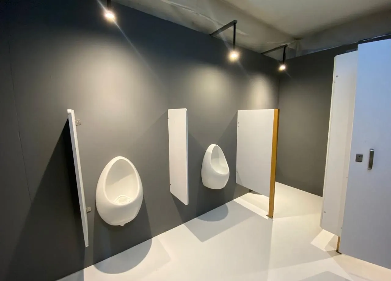 Mingitorios de porcelana con divisores blancos en un baño portátil de lujo gris