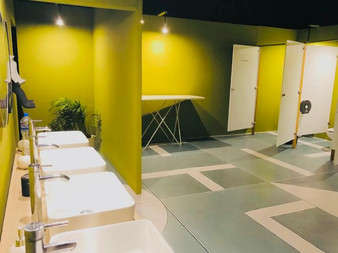 Fila de lavabos blancos con llaves cromadas en un baño de lujo VIP verde olivo