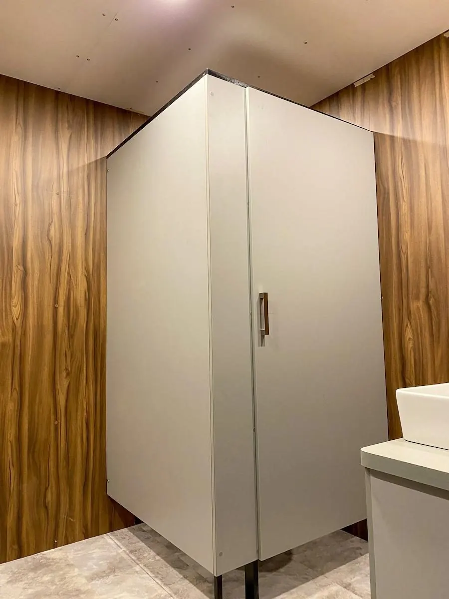 Cubículo blanco y paredes de madera dentro del baño remolque VIP