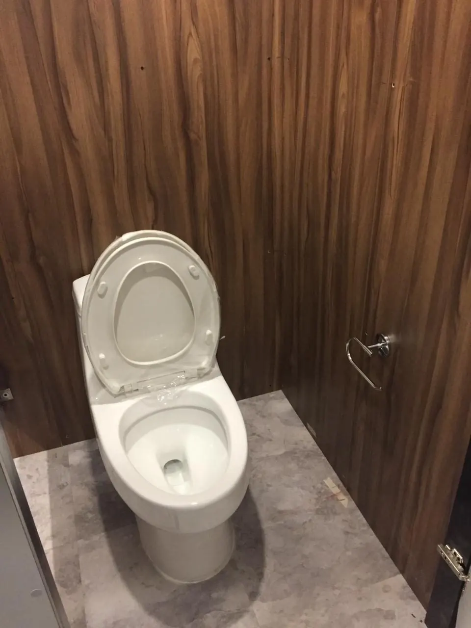 Inodoro de porcelana en un cubículo con paneles de madera del baño remolque