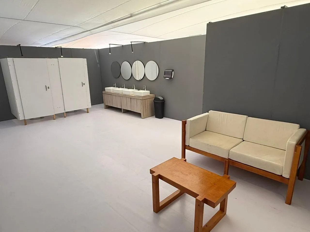 Sala de espera con sillón dentro de un baño de lujo VIP, con lavabos al fondo